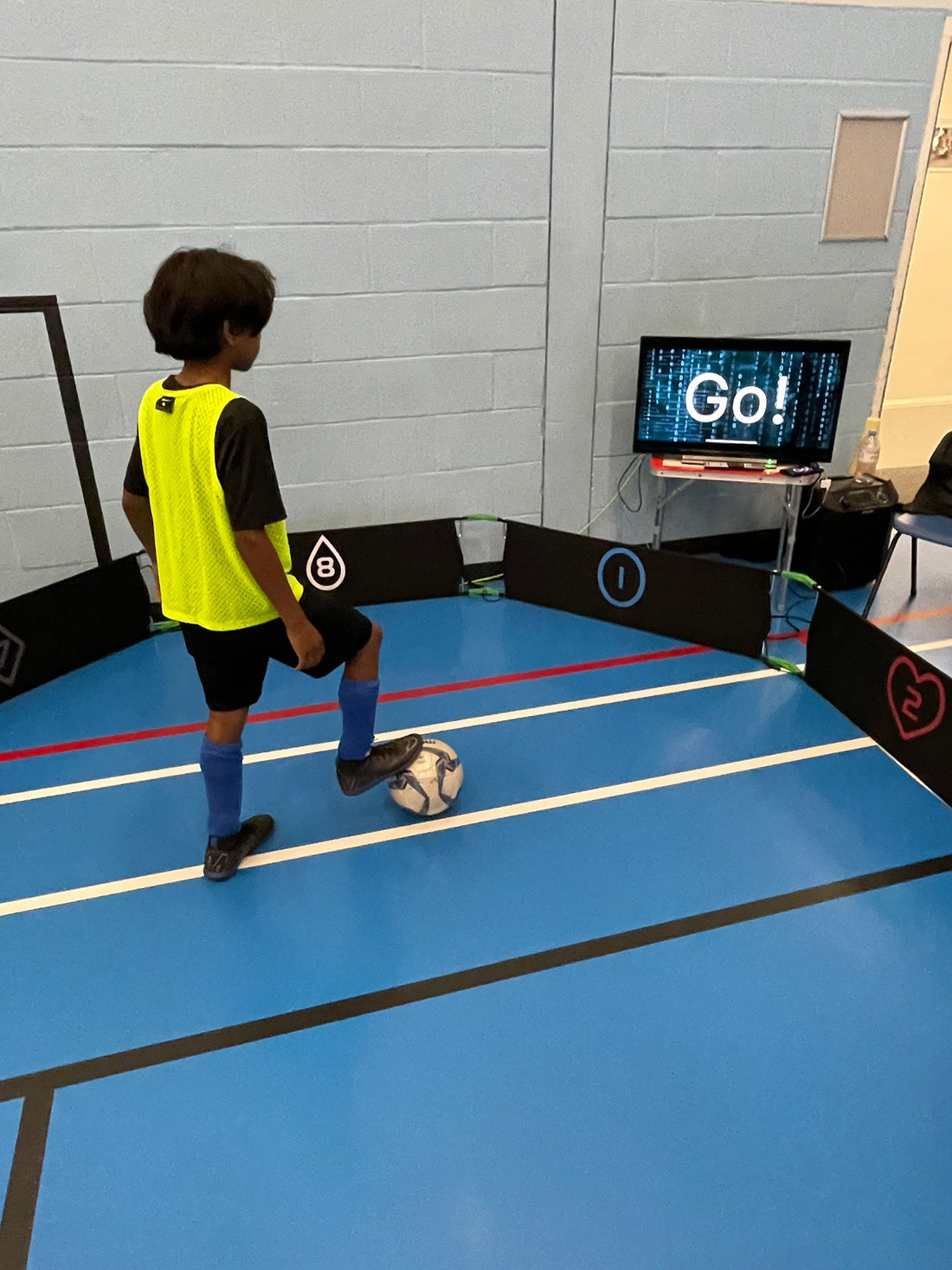 Jonge voetballer doet cognitieve voetbaltraining met reactiedoelen